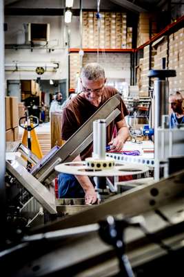 Worker next to a small assembly line for stickers 