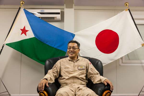 Airforce captain and commanding officer of the counter-piracy mission’s air-support unit Masahisa Motomura beneath the flags of Djibouti and Japan