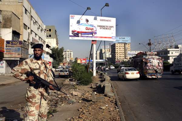 Pakistani ranger guards beneath a TV news billboard on a Karachi street 