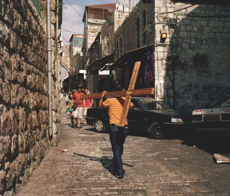 A man carries a crucifix through old Jerusalem, following Jesus’s path prior to his crucifixion  